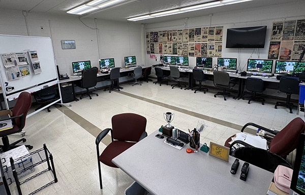 Image depicting a spacious room with computer setups lining the walls.