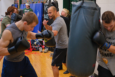 Students exercise with punching bags in a gym